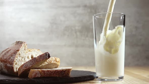 Milk is Poured Into a Glass and Fresh Bread
