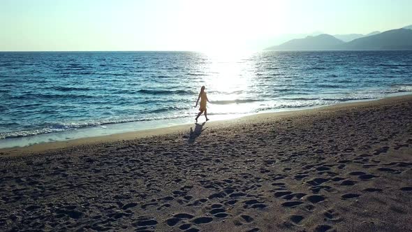 Aerial Drone Footage of a Girl Walking Along a Lonely Beach