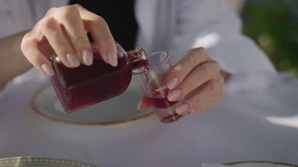 Female Hands Pouring a Shot of Red Tincture From a Small Bottle alt