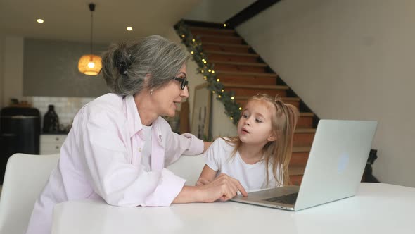 Child and Granny Looking at the Camera with Laptop alt