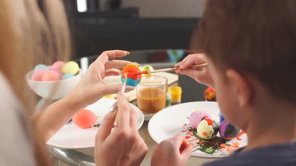 Young Mother and Her Son Having Fun While Painting Eggs for Easter