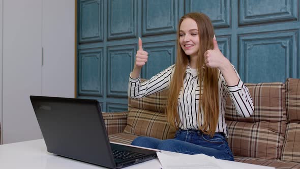 Young Business Woman Sitting at Workplace Home Office Making Video Call on Laptop Shows Thumbs Up alt