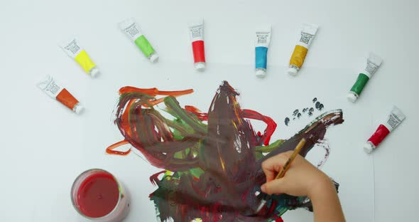 Closeup Footage Top View of How a Little Boy Draws with a Brush on a White Sheet of Different Colors alt