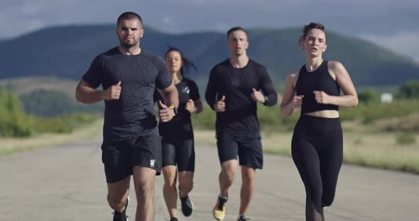 Multiethnic Group of Athletes Running Together on a Panoramic Countryside Road alt