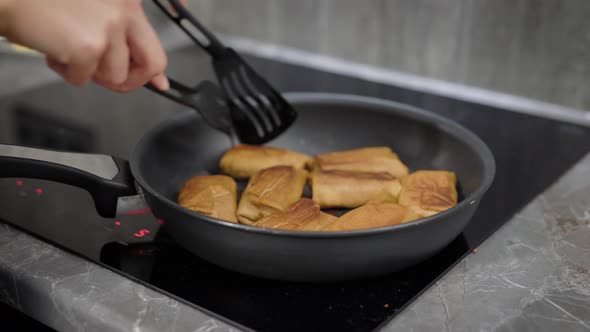 Woman Is Roasting Pancakes with Fillings on a Pan in Her Domestic Electro Cooker alt