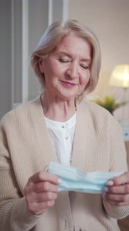 An Elderly Woman in a Medical Mask Looks at the Camera