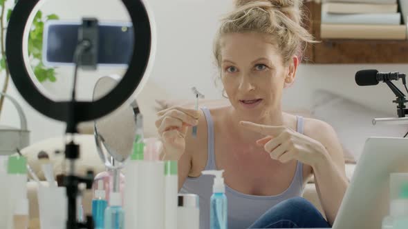 Blonde smiling woman influencer blogger recording a video tutorial on smartphone