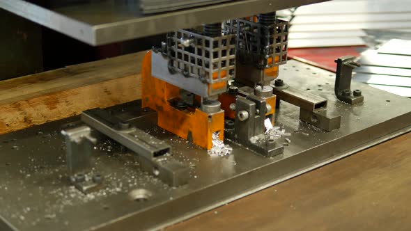 Worker making holes in metal plates with a punching drilling machine alt