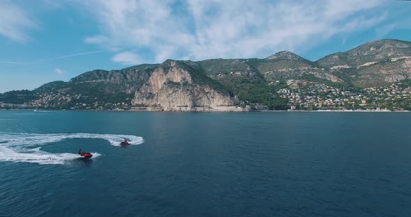 Aerial View Of Two Jet Ski Ride Near Super Yacht At Sunset.