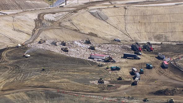 Aerial shot of trucks and tractors working in landfill alt