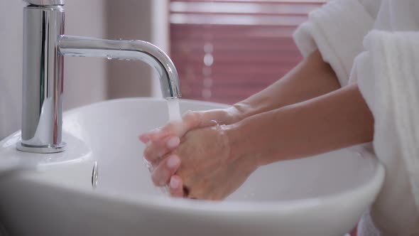 Closeup Female Hands Young Unrecognizable Woman Stands Near Washbasin in Bathrobe in Modern Bathroom alt