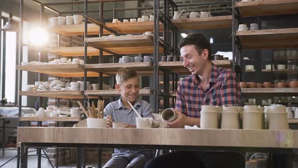 Cute Middle Age Man with His Little Son Having Fun in the Pottery alt