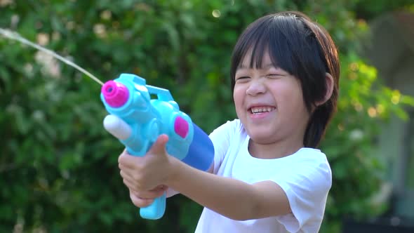 Cute Asian Child Playing With Water Gun In The Summer alt