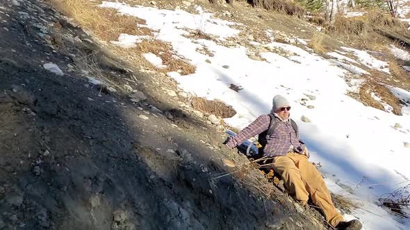 Man sliding down hill falls at the bottom