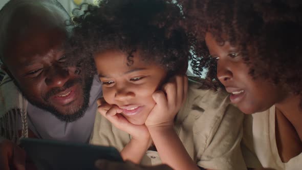 Little Boy and Parents Watching Movie on Tablet in Evening at Home alt