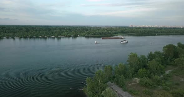 Drone Flight Over the River Overlooking the Tug Barge and Sailboat in the Evening, Sunset. Ukraine