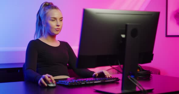 Beautiful E-sport Gamer Girl with Headset Playing Online Video Game on PC alt