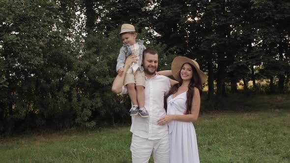 A Handsome Dad with Short Dark Hair in a White Shirt and Shorts, an Attractive Mum with Long Dark