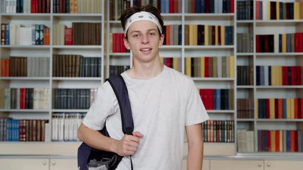Single Portrait of Smiling Confident Male Student Teenager Looking at Camera in Library alt