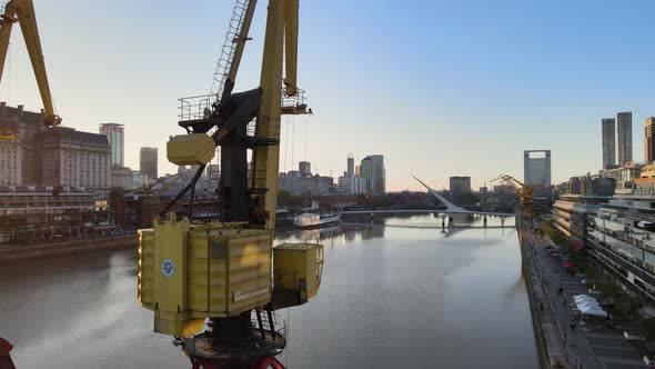 Aerial orbiting left around cranes and revealing Puerto Madero waterfront at sunset alt