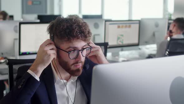 Close Up Portrait of a Technical Customer Support Specialist Talking on a Headset While Working on a alt