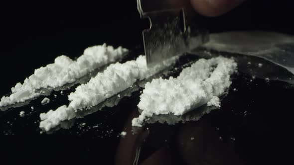 Lines of cocaine being cut with razor blade on table top alt