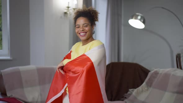 Middle Shot Portrait of Smiling African American Woman Wrapping in Canadian Flag Looking at Camera alt