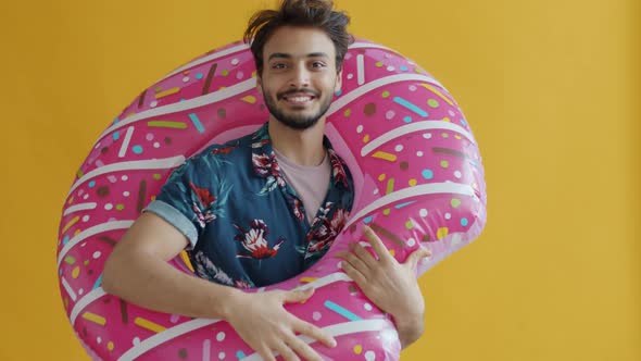Slow Motion of Happy Arab Guy Holding Swimming Donut and Waving Hand Invition on Vacation alt