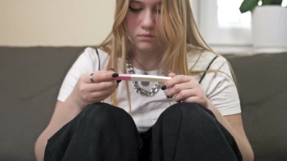 Teenage Girl Looks at the Result of a Pregnancy Test and Cries