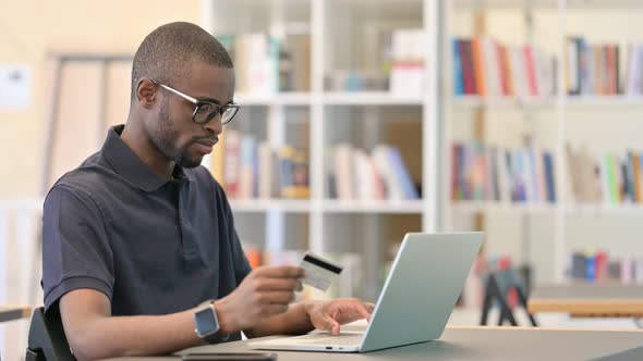 African Man Having Online Payment Failure on Laptop in Library alt