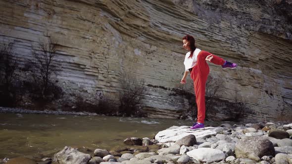 Girl Does Splits on Background Mountain River and Rocks alt
