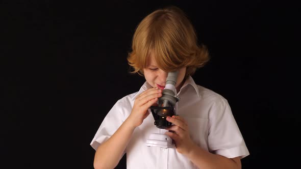 Young first graders experiment with microscope at home. against black background