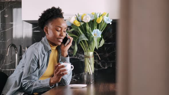African Woman Talking on Mobile Phone While in the Kitchen alt