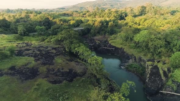 Drone footage of a single road, a small bridge and a river during a sunrise. alt