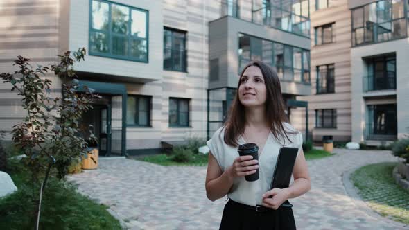Young Happy Business Woman with Tablet and Drinking Coffee While Walking Slow Motion alt