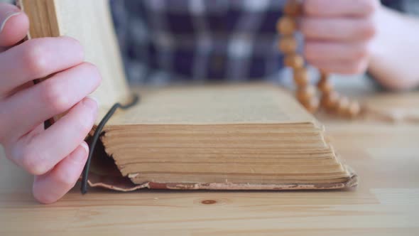 Close Up of a Rosary in the Hands of a Woman and the Open Bible alt