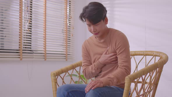 Asian man suffered a heart attack, resulting in chest pain and illness on the sofa. alt