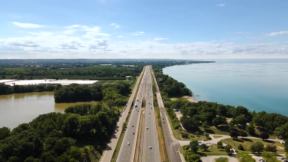 Aerial view of cars driving on a highway next to a beautiful emerald lake. Top view of a cars drivin alt