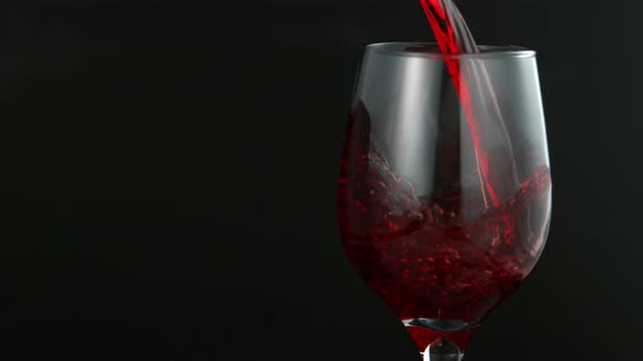 Pouring Red Wine in Super Slow Motion on Black Background alt