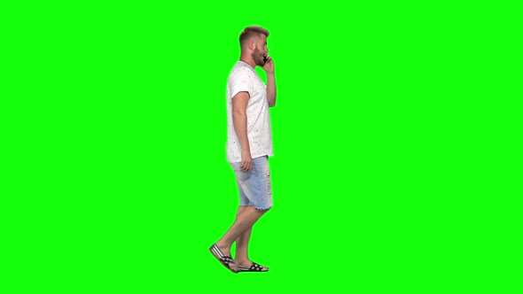 Bearded Guy Calmly Walking and Talking on Mobile Phone on Green Screen Background. Chroma Key alt
