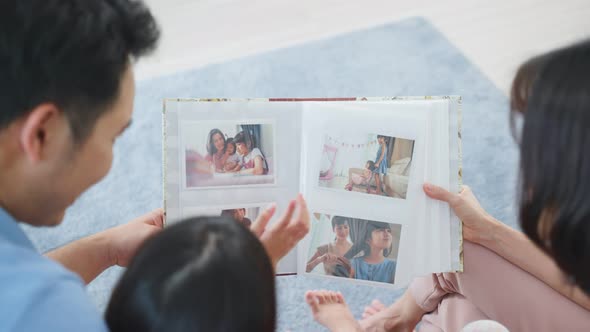 Asian family look at photographs on old picture album recalls the past. alt