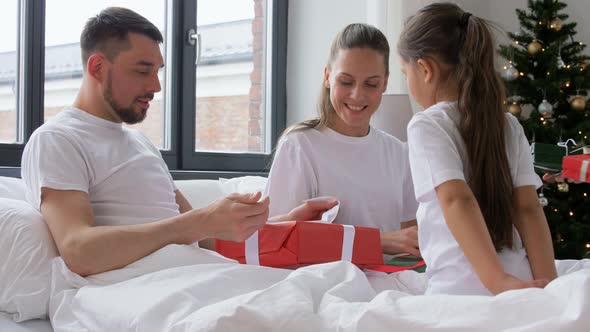 Happy Family with Christmas Gifts in Bed at Home alt