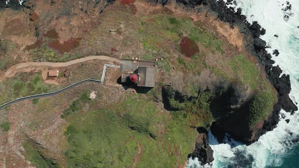Cinematic Overhead View on a Lighthouse with Red Roof on Green Rocky Island,  alt