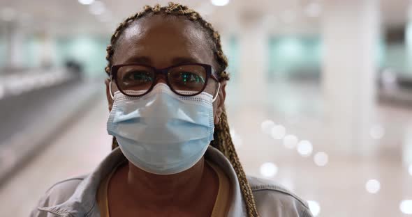 Mature african woman looking on camera while wearing safety face mask for coronavirus outbreak at ai alt