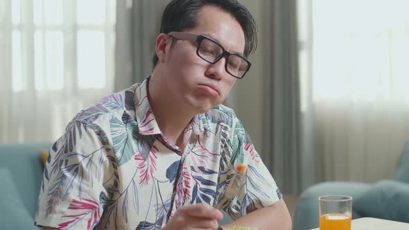 Close Up Of Asian Man Holding His Cheek And Shaking Her Head Due To Hating Eating Healthy Food alt