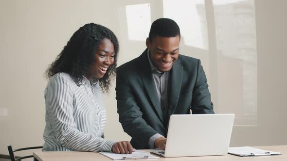 Overjoyed Young African Male Mentor and Mixed Race Female Intern Looking at Laptop Screen Excited By alt