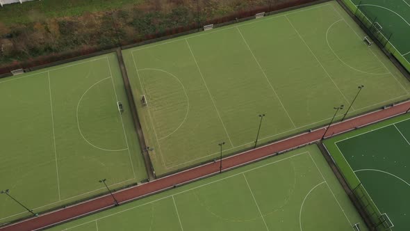 Aerial view that turns around a complex of multiple sport fields with artificial green grass alt