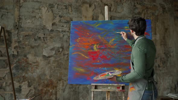 Man is an Artist Holding a Brush and Drawing an Abstract Picture alt