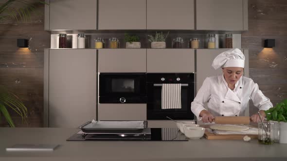 Chef Rolling Out Dough for Pizza in Kitchen alt