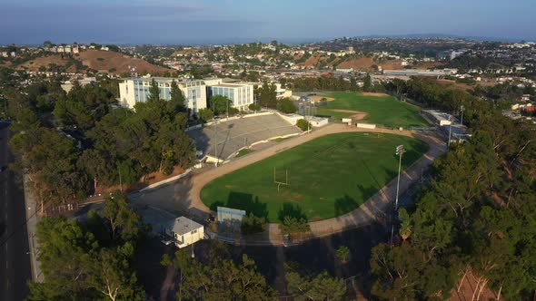 Epic Drone Pullback from a High School on Top of a Hill with a Football Field Revealing Residential alt